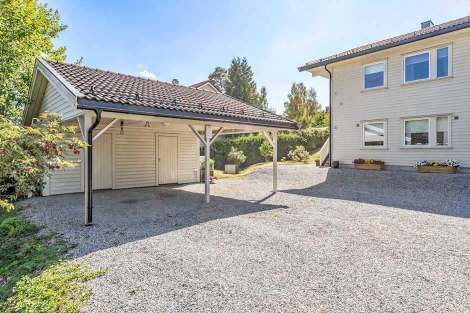 Carport med boder og gruslagt gårdsplass ved boligen
